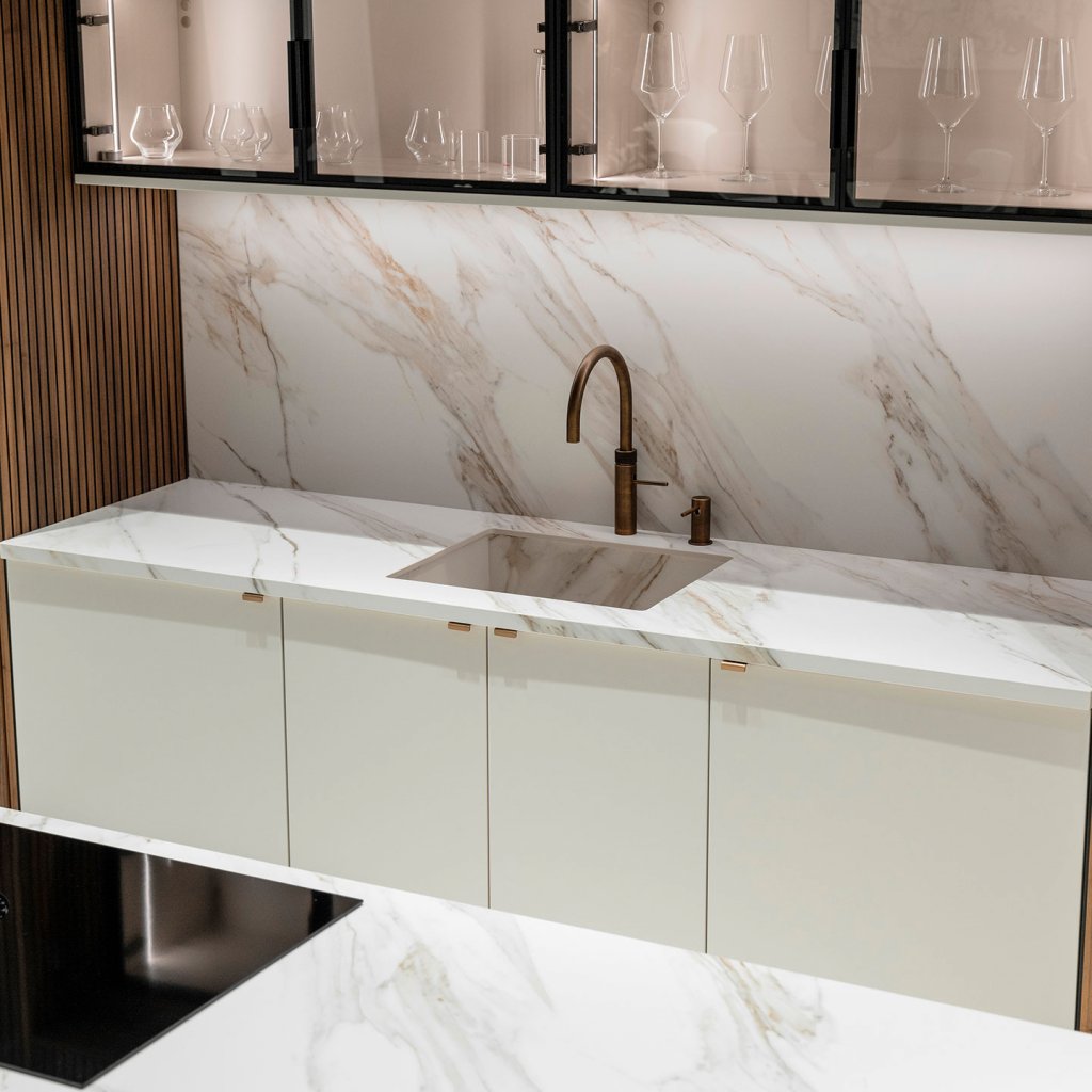 O porcelanato Ceratop Dolomiti na bancada e ilha desta cozinha de luxo oferece uma combinação única de beleza e praticidade