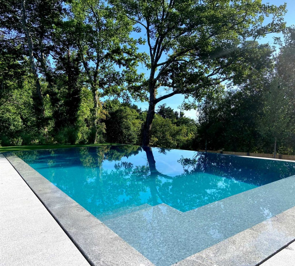 Granito cinza com acabamento antiderrapante: uma escolha clássica e duradoura para bordas e escadas de piscina, com sobriedade estética e alta resistência à umidad