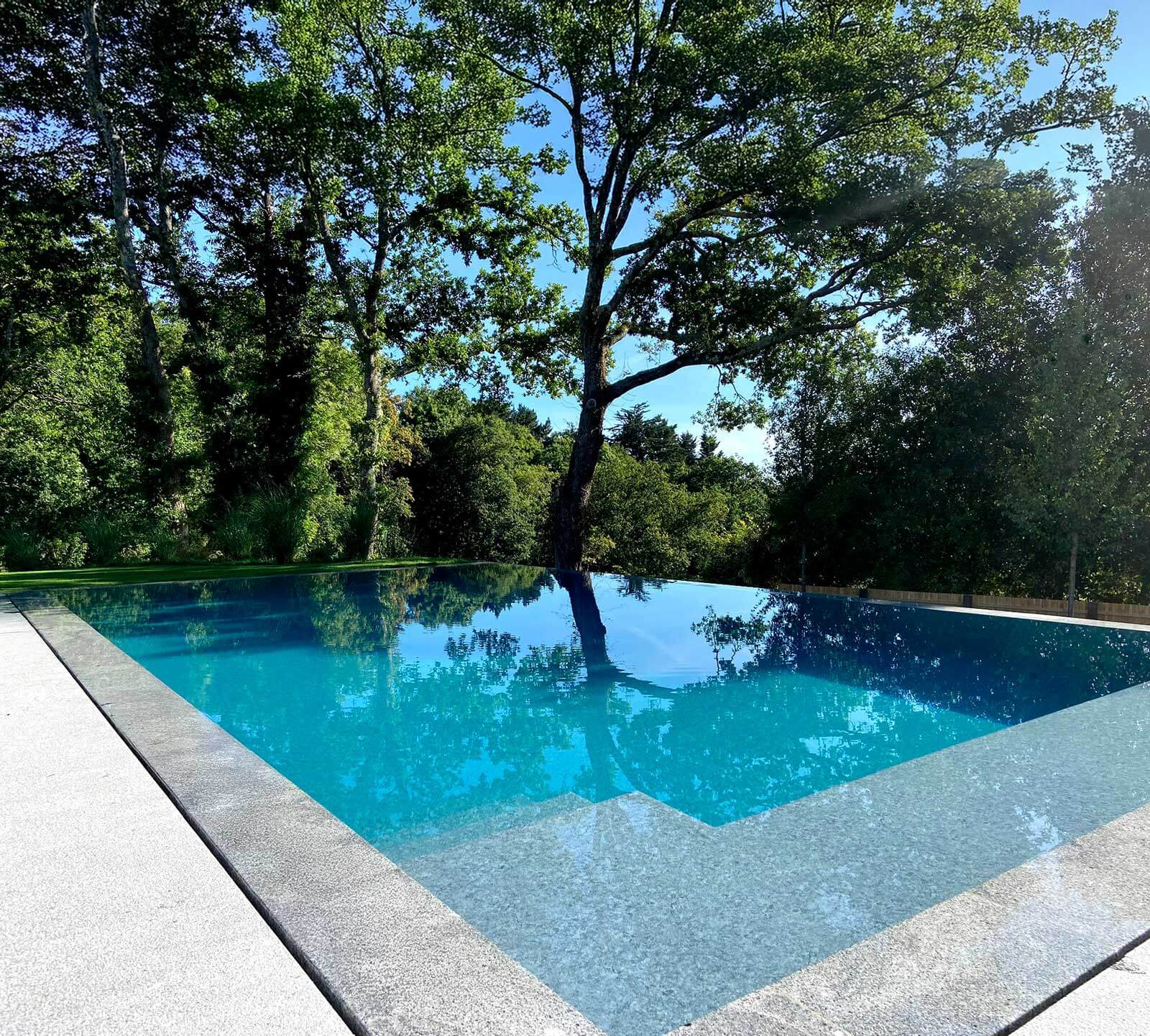 granito-piscina Granito cinza com acabamento antiderrapante: uma escolha clássica e duradoura para bordas e escadas de piscina, com sobriedade estética e alta resistência à umidad