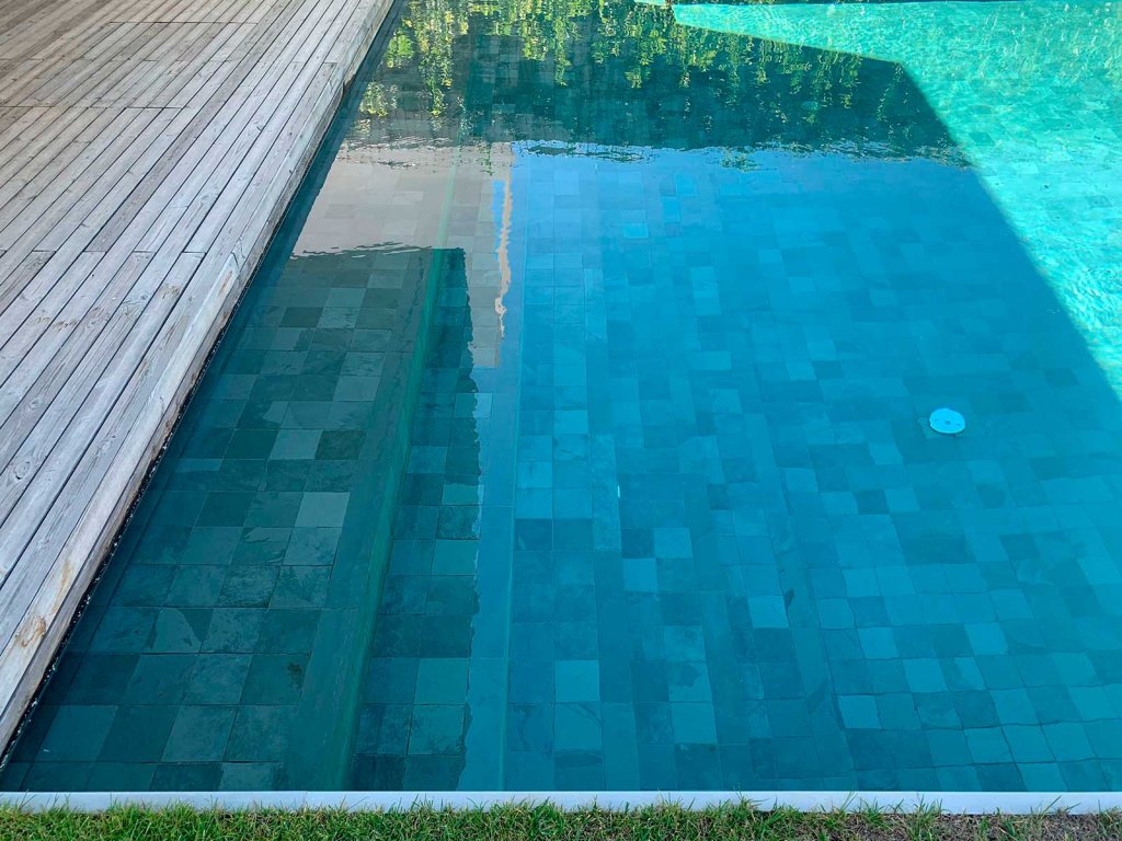Piscina revestida com mosaico de ardósia celeste: tonalidades azul-esverdeadas que intensificam a cor da água e criam um efeito visual natural e envolvente
