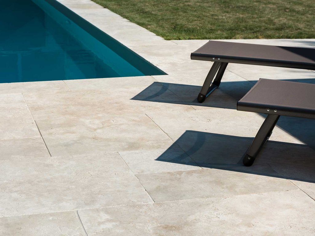 Borda de piscina em travertino Avelã: superfície naturalmente antiderrapante e sempre fresca ao toque, ideal para conforto e segurança ao redor da água